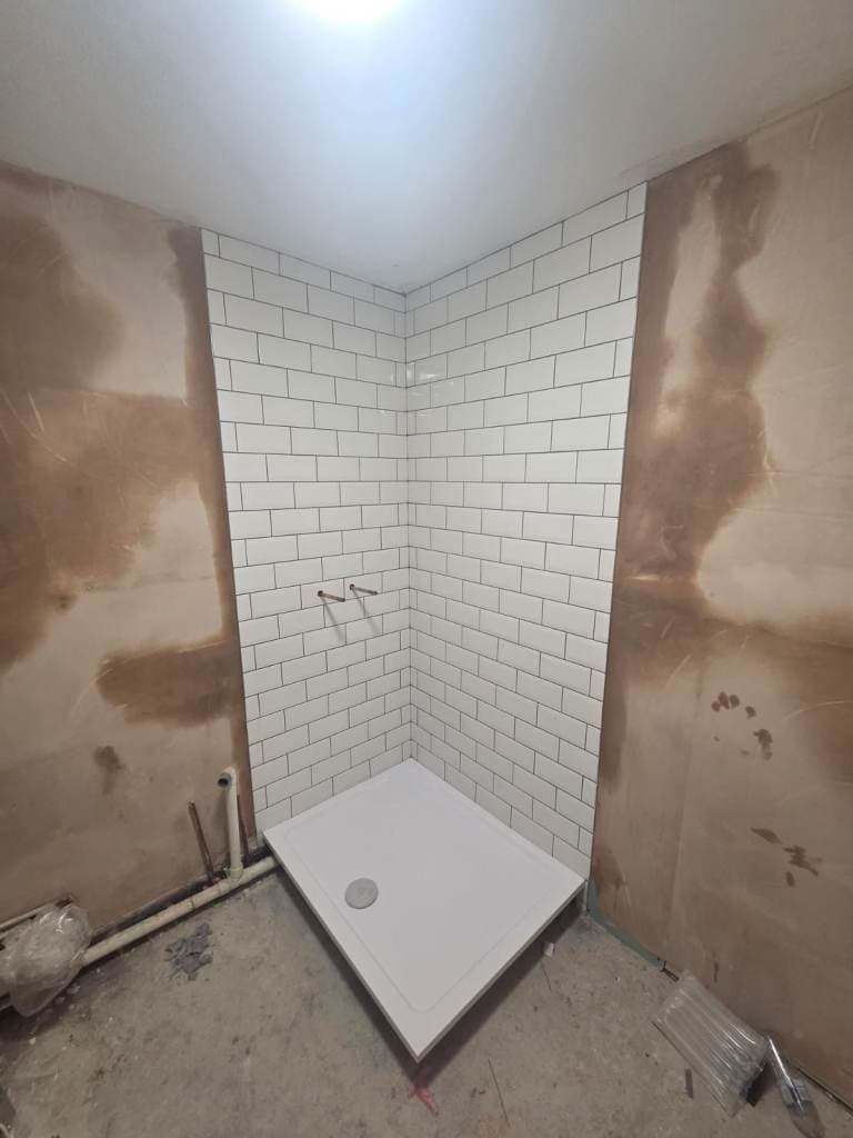 White metro tile shower corner mid-installation, shower tray fitted